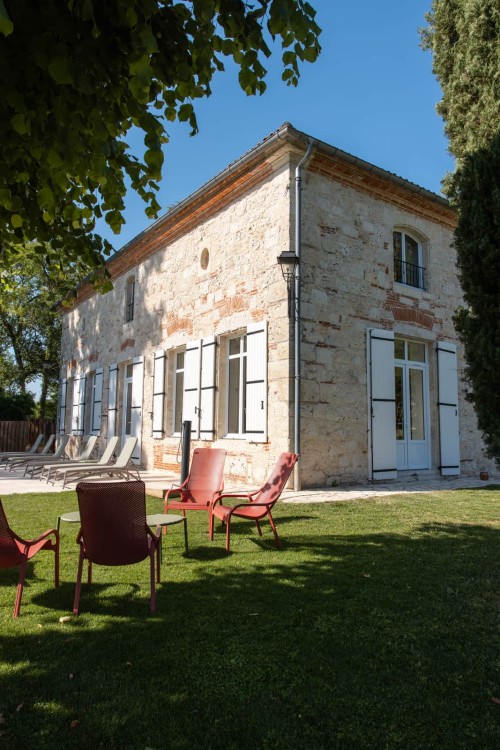 Fauteuils au jardin devant la façade en pierre du gîte, pause de séminaire en Lot-et-Garonne
