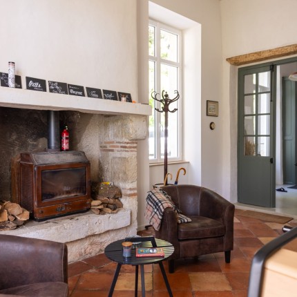 Salon avec poêle à bois et fauteuils club de la Maison de Ninette