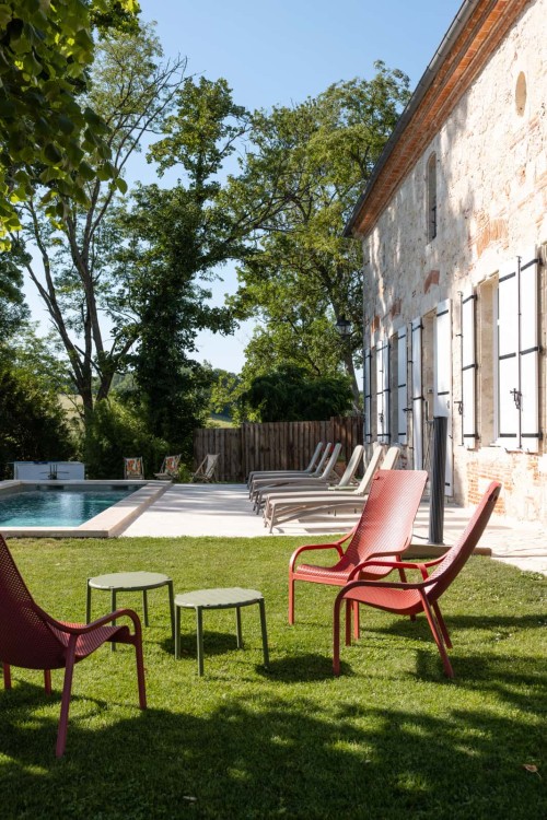 Fauteuils dans le jardin et piscine chauffée en arrière-plan, réunion de famille en Lot-et-Garonne