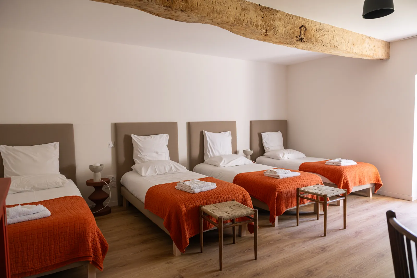 Chambre Arbousiers avec quatre lits simples sous une poutre ancienne, gîte de groupe à Castelculier